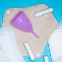 Menstrual products and supplies (pads, tampons, menstrual cups) on a colorful background.