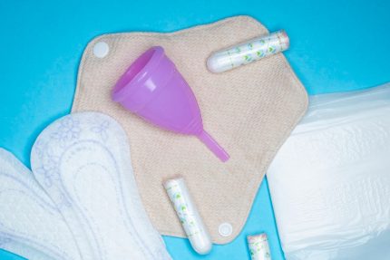 Menstrual products and supplies (pads, tampons, menstrual cups) on a colorful background.