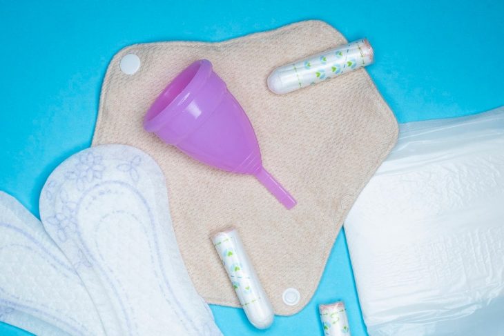 Menstrual products and supplies (pads, tampons, menstrual cups) on a colorful background.