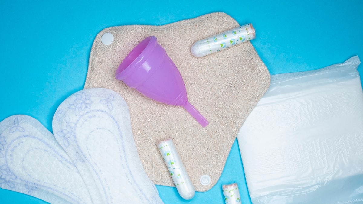 Menstrual products and supplies (pads, tampons, menstrual cups) on a colorful background.